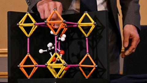 A model showing metal-organic frameworks made of yellow and red tubes and nodes.