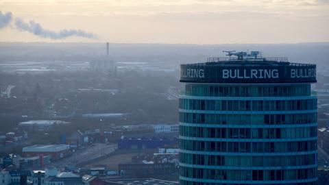 The Birmingham skyline with the Rotunda in the foreground and a smoking chimney in the background