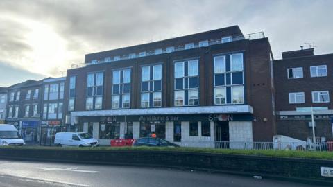 A general view of St Matthew's Street in Ipswich looking over to the Spoons restaurant. Cars can be seen travelling on the road. 