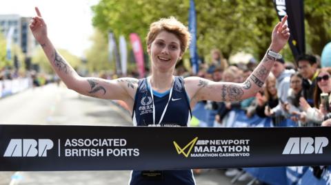 Woman crossing the finish line at Newport Marathon