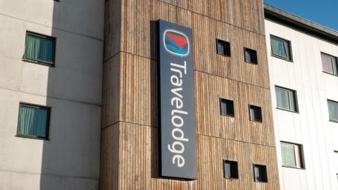 Travelodge logo on side of brown and white hotel