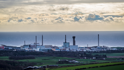 Sellafield nuclear site with the sea behind and taken from a distance away so there are fields clearly visible 