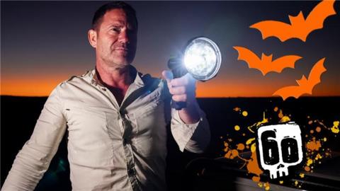 Steve backshall holding a torch against an orange sunset
