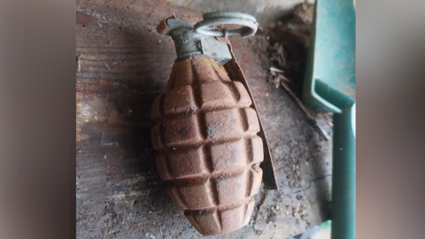 A hand grenade on a wooden shelf inside a shed.