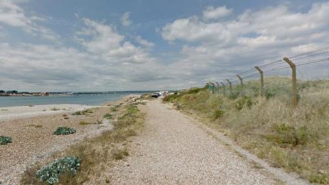 Shingle path and beach with expanse of water to the left.