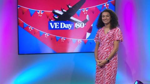 Nina in the studio with a VE Day graphic in the screen