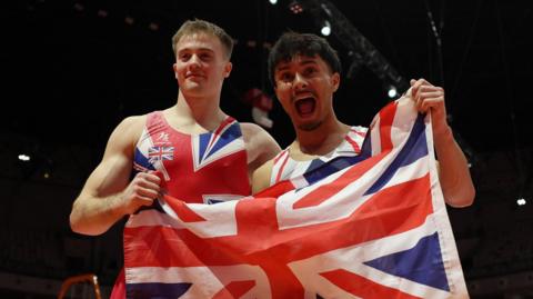 Luke Whitehouse (left) and Jake Jarman (right) celebrate holding a gb flag