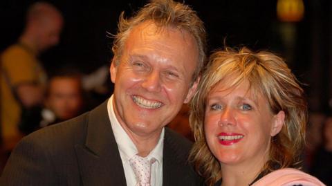 Sarah Fisher, with her blonde hair tousled in a long crop and wearing a pink shawl, with Anthony Head who is wearing a black jacket, white shirt and tie.
The pair have big smiles for photographers.