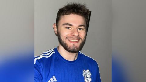 Selfie o Rhys Thomas, bachgen ifanc yn gwenu ac yn gwisgo crys pêl droed Caerdydd