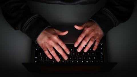 A close up of two hands typing on a laptop keyboard.