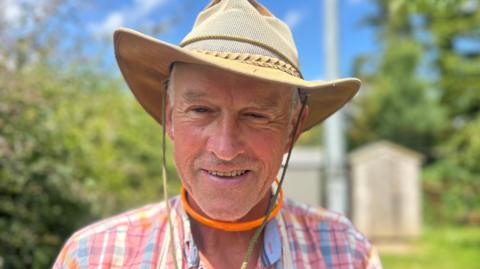 Man wearing a sun hat in front of a wind turbine