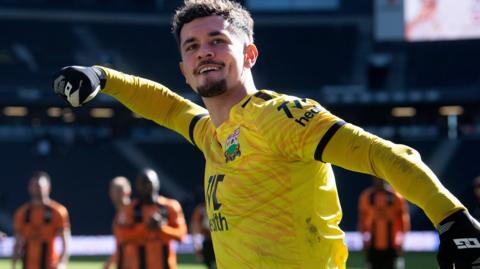Cieran Slicker celebrates with Barnet fans after a match wearing a yellow goalkeeper jersey
