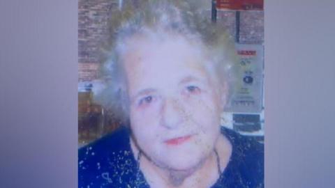 An older lady with grey hair wearing a blue top