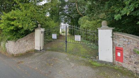 Front entrance gate to Tidcombe Hall in Tiverton with postbox to the right