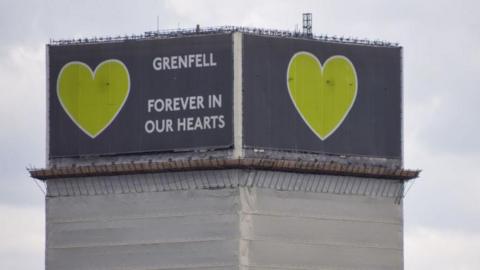 The top of Grenfell Tower with symbolic green heart. The wording at the top of the tower states "Grenfell Forever in our hearts"