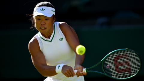 Llun o Mimi Xu yn chwarae tenis, ar fin ergydio'r bêl. 