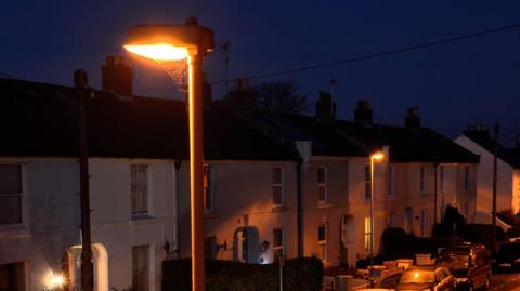 A streetlight glows orange on a street at night.