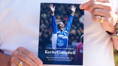 An Everton supporter holds the order of service