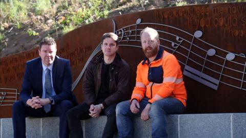 Councillor Kevin Johnston, musician Marty Longstaff and artist Chris Brammall sit by the newly installed artwork.