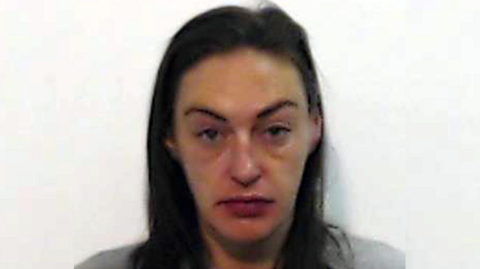 A police mugshot of Natasha Smith who is in her late 30s with long, brown hair
