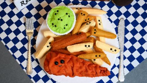 A plate of fish, chips and mushy peas, with smiley faces on every piece of food.