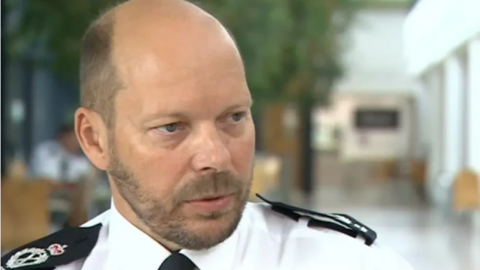 Photo of Gloucestershire's chief constable Rod Hansen who has a bald head and is wearing a police white shirt with black shoulder pads.