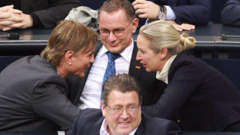 AfD leaders huddle together. Clockwise from left:  AfD faction parliamentary manager Bernd Baumann;  co-chairman Tino Chrupalla; co-chairwoman Alice Weidel; deputy chairman Stephan Brandner.