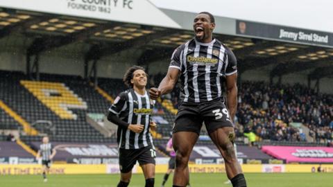 Lee Ndlovu jumps in the air and clenches his fist in his right hand in celebration of a goal