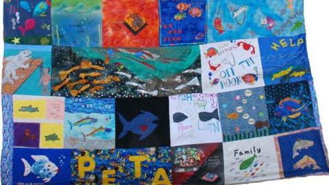 Patchwork quilt featuring fish-themed squares showing a variety of images  or slogans.