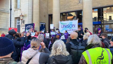 A group of protesters holding Unison signs stand outside Shire Hall in Gloucester