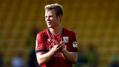 West Bromwich Albion striker Aune Heggebo claps his hands at the end of a match. He is wearing a red away shirt.