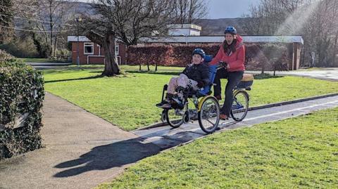 Two people smiling while riding a wheelchair bike