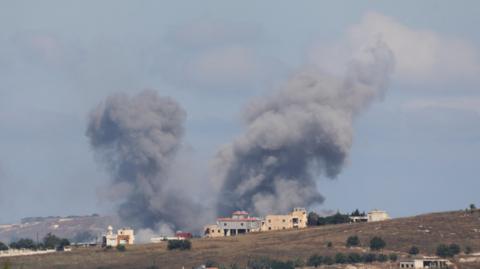 Plumes of smoke are seen above a house