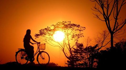  An Indian girl rides a bicycle during sunset in Joypur village, on the outskirts of Agartala, the capital of northeastern state of Tripura on December 30, 2017. /