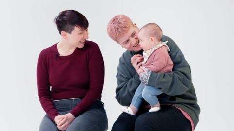 Two women smiling and talking to their baby. 