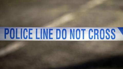 A close up of blue and white police tape with the words: "Police Line Do Not Cross"