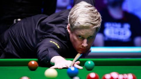 Neil Robertson leans on a snooker table and aims his cue at a ball