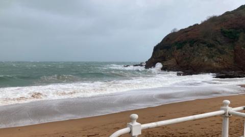 A spotless sandy beach lashed by the waves of a winter storm. 