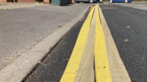 Two sets of double yellow lines painted on the same stretch of road, overlapping.