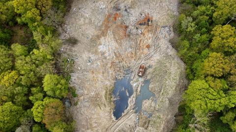 A drone shot showing waste flanked by trees 