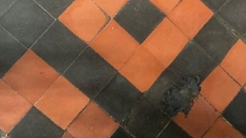 Red and black square floor tiles with black charred sections.