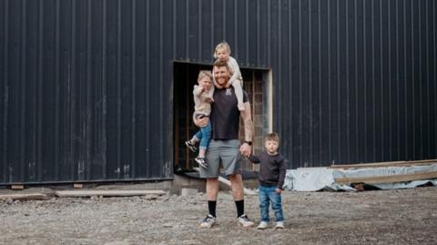 Picture of Rhys Jones and his family outside his farm. 