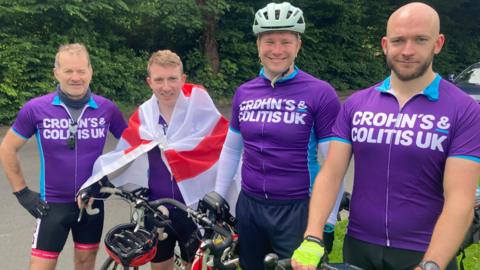 Four cyclists smile at the camera