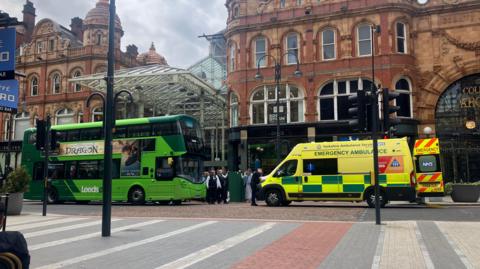 A stationary bus on Vicar Lane opposite an ambulance.