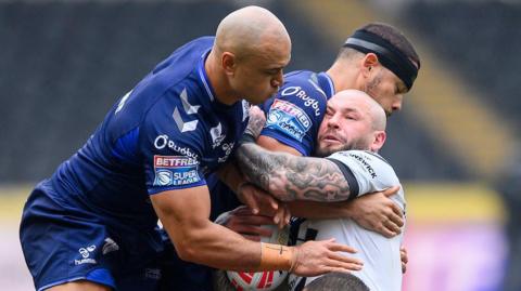 Zak Hardaker grimaces as he is driven backwards by the Toulouse defence