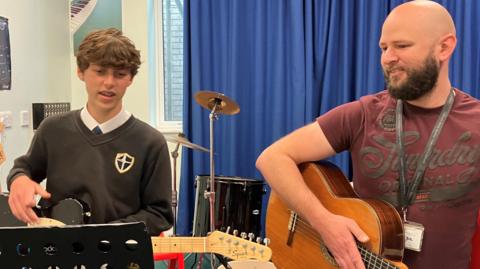 Student and teacher playing electric guitar