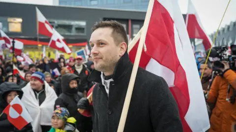 Greenland's Prime Minister Jens-Frederik Nielsen waves a flag during a protest against U.S. President Donald Trump’s demand that the Arctic island be ceded to the U.S., calling for it to be allowed to determine its own future, in Nuuk, Greenland, January 17, 2026