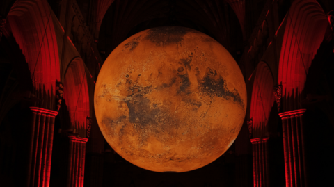A large red coloured orb suspended between stone arches