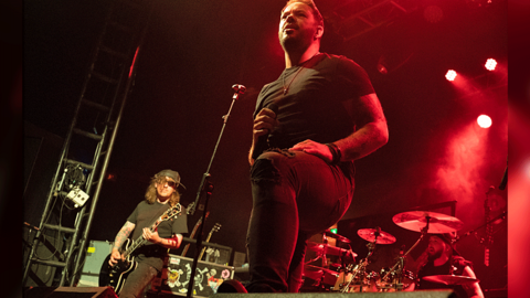 Those Damn Crows perform on stage behind a dark set including red lights