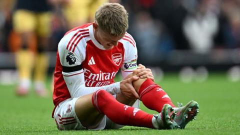 Martin Odegaard holds his left knee after injuring it